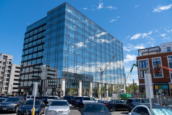 Building with sky reflected on windows and cars in foreground