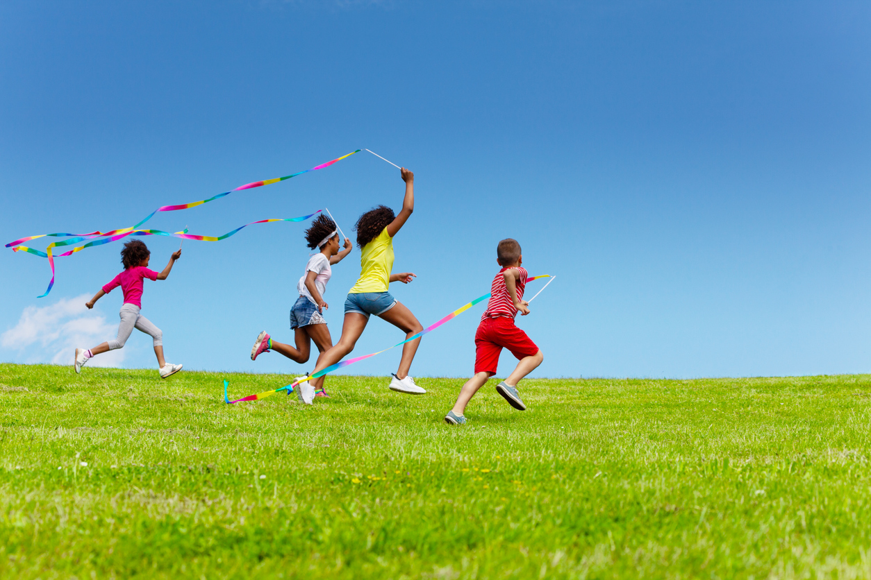 Children running on a hillside with flags.