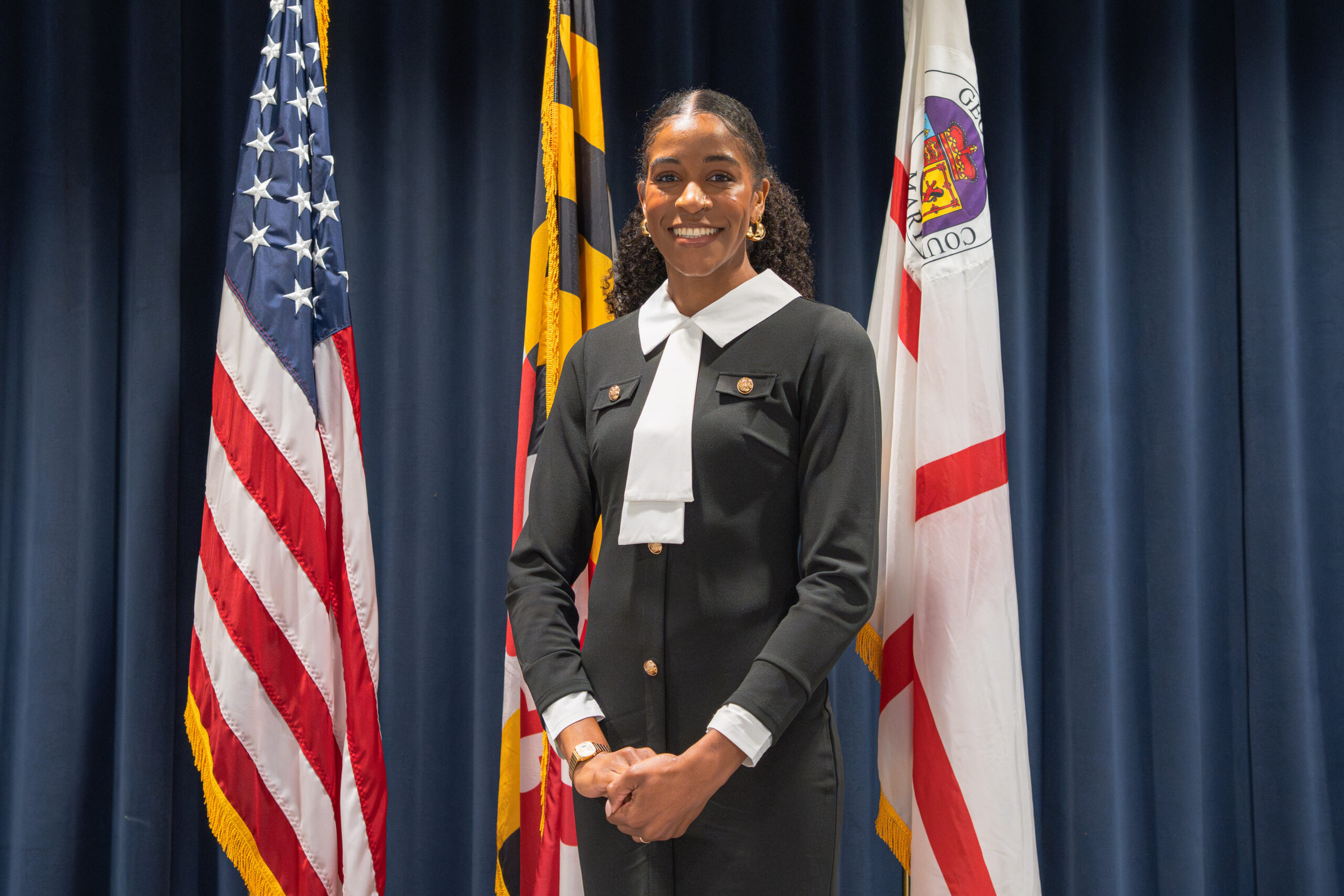 Commissioner Jenkins standing before the flag of the United States, the Maryland State flag, and the flag for Prince George's County, MD.