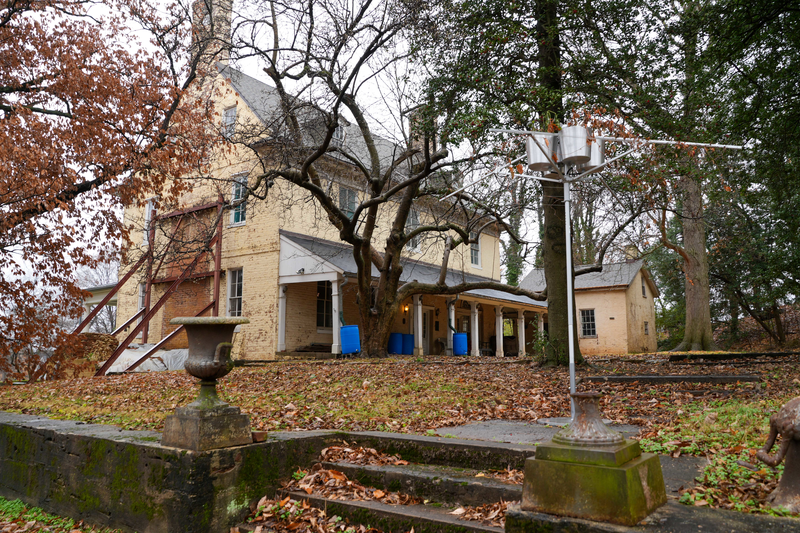 Photo of yellow historic property with steps and leaves